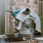 grey and teal Makita miter saw on table outdoors during daytime